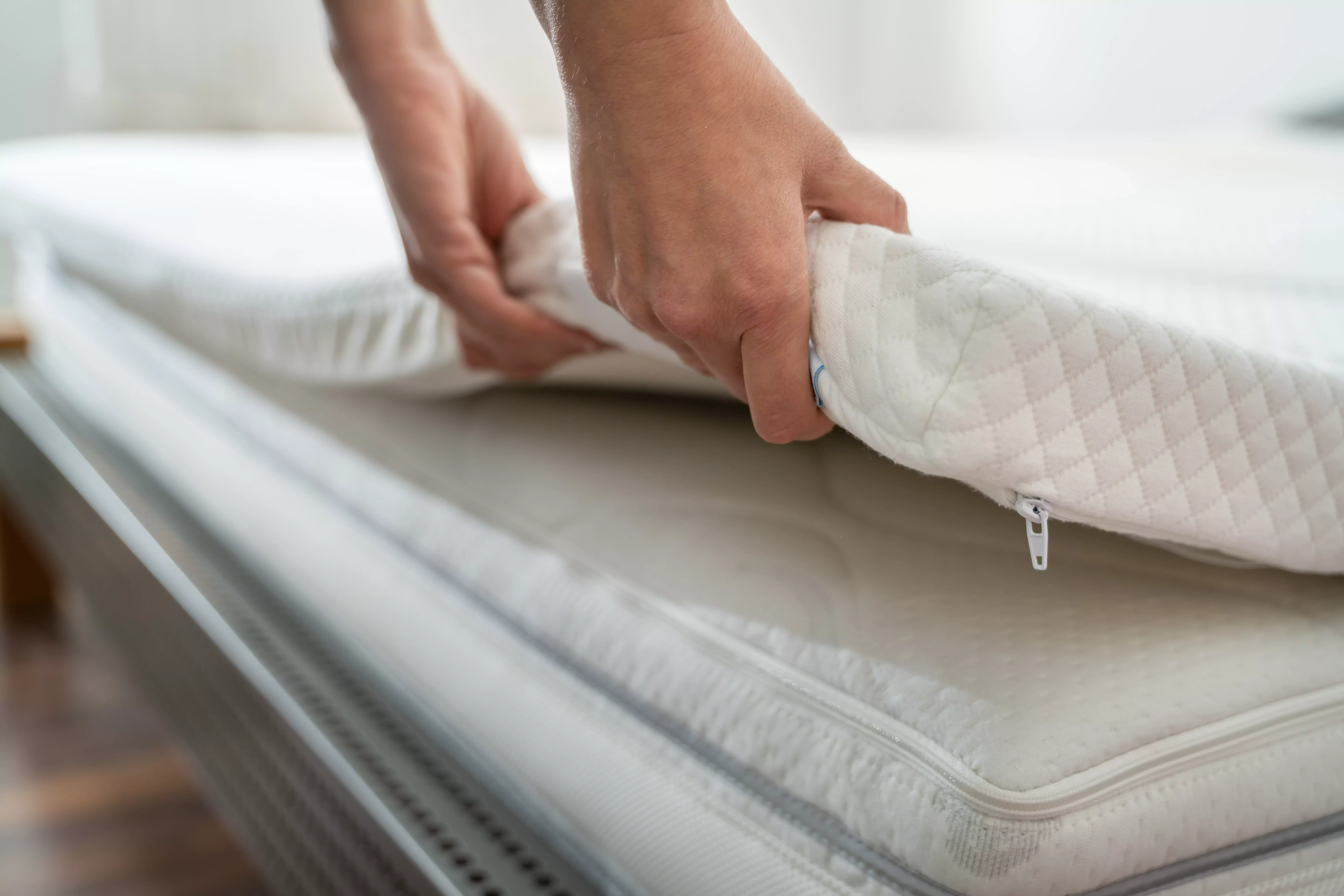 Gros plan sur une personne plaçant un surmatelas sur un matelas - idéal pour un confort supplémentaire et une protection du matelas.