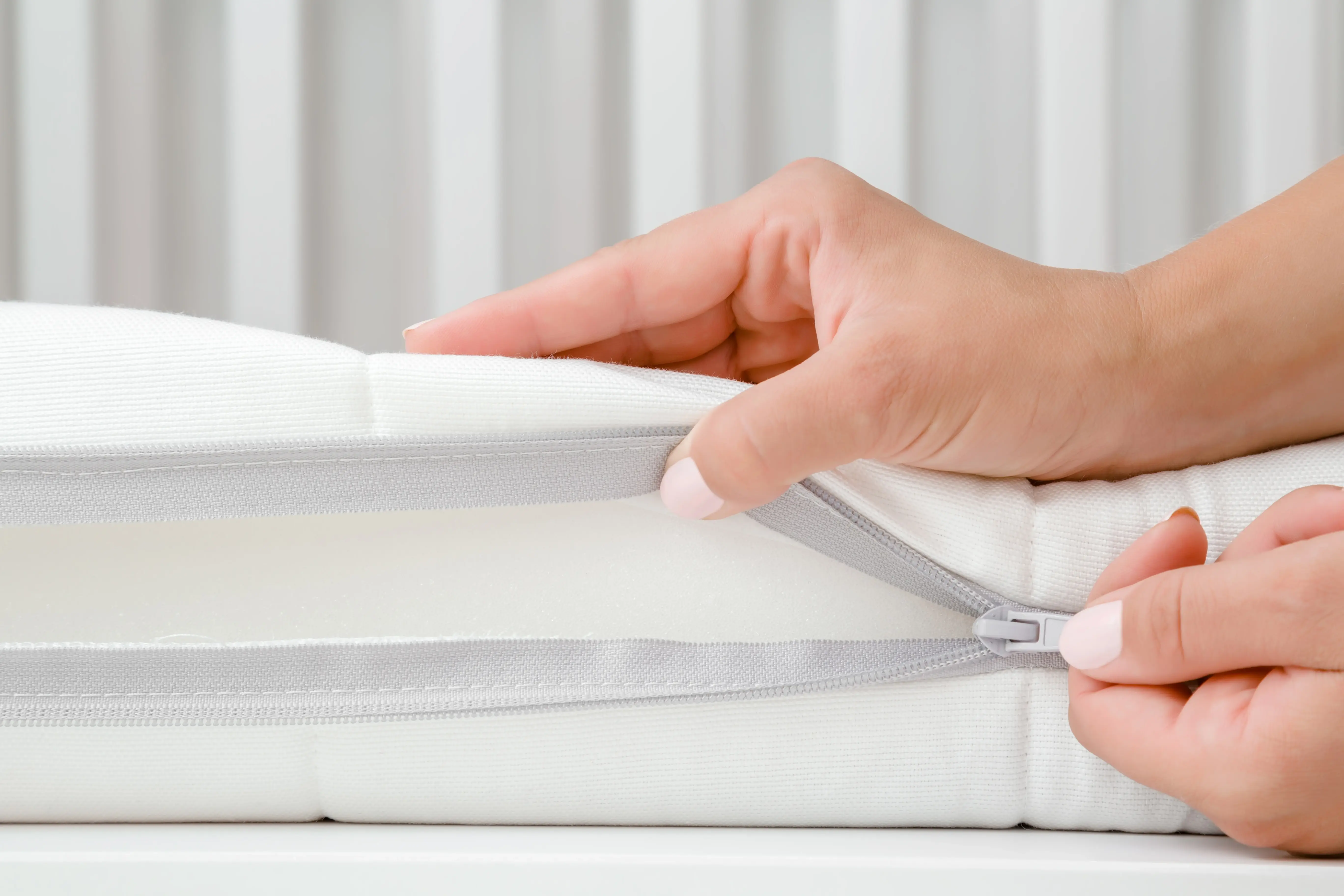 La main ouvre la fermeture éclair d'un surmatelas - montre la housse amovible pour un entretien et une protection faciles.